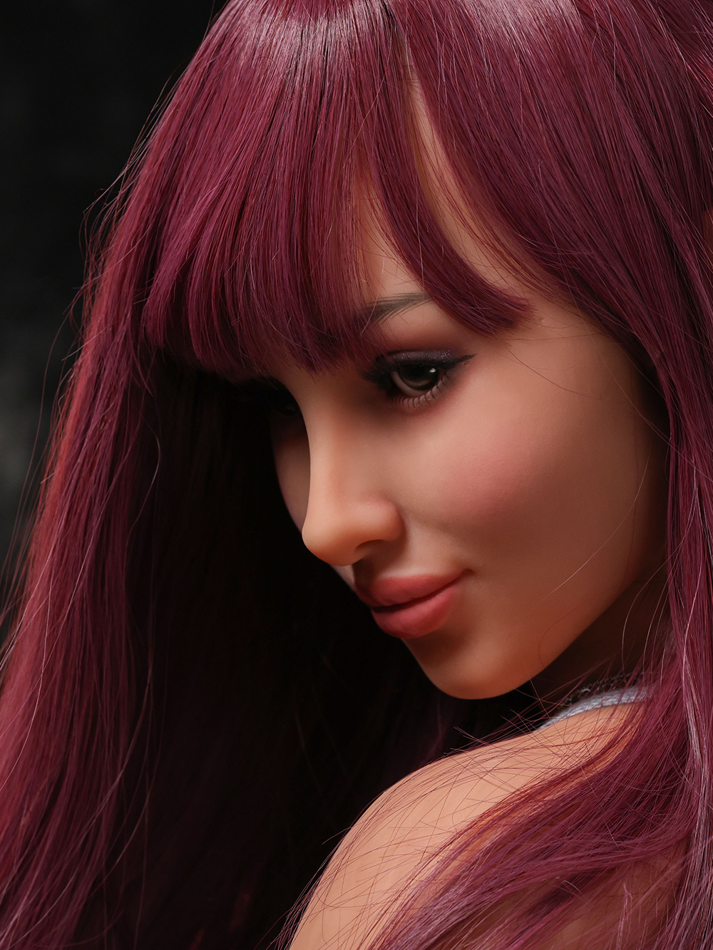 Close portrait of Alaya, blunt fringe just above her brow and a brown eye catching the key light