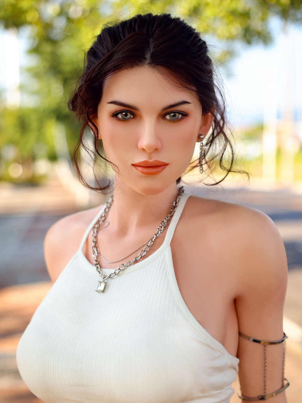 Elena close in with green leaves and a paved path behind her, the silver chain flat across her collarbone